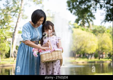 Una nonna asiatica felice e gentile sta camminando e si diverte nel parco verde con la sua adorabile nipote durante il fine settimana. Concetto di legame familiare Foto Stock