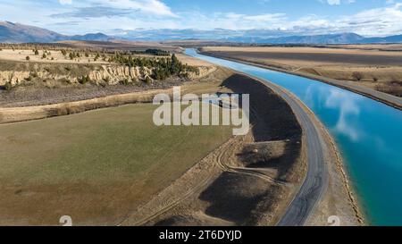 Vista aerea del canale Pukaki Hydro Power Scheme nella campagna di Twizel che corre in parallelo con la catena montuosa di Ben Ohau, ora ricoperta Foto Stock