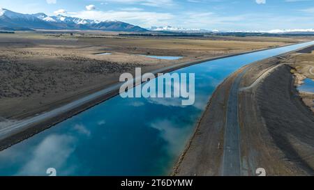 Vista aerea del canale Pukaki Hydro Power Scheme nella campagna di Twizel che corre in parallelo con la catena montuosa di Ben Ohau, ora ricoperta Foto Stock