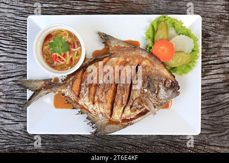 Pomfret fritto con salsa di pesce estratto dall'alto su una consistenza rustica Foto Stock