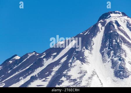 Primo piano di una cima innevata di montagna nel cielo blu, che si affaccia sulla Laguna Miscanti, nelle Ande, nel nord del Cile. Foto Stock