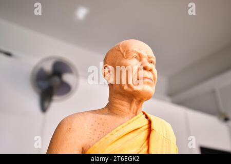 Una statua in miniatura di cera di un vecchio monaco calvo in abito arancione. A Wat Saket, il Monte d'Oro. A Bangkok, Thailandia. Foto Stock