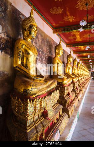 Una fila infinita di statue di Buddha seduto in oro fiancheggiano un portico che circonda il tempio. A Wat Suthat Thepwararam Ratchaworamahawihan a Bangkok, Tha Foto Stock