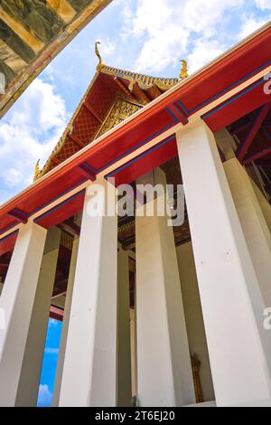 Vista esterna dell'incombente tempio con alte colonne bianche. A Phra Ubosot Wat Suthat a Bangkok, Thailandia. Foto Stock
