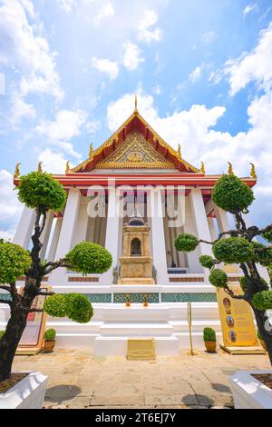 Vista esterna dell'incombente tempio con alte colonne bianche. A Phra Ubosot Wat Suthat a Bangkok, Thailandia. Foto Stock