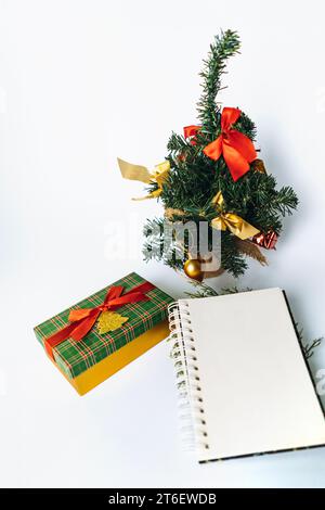 aprire il blocco note con un foglio vuoto per il testo della lista dei desideri. albero di natale decorato sullo sfondo Foto Stock