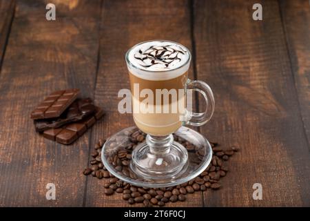 Caffè a più strati in tazza di vetro su un tavolo di legno Foto Stock