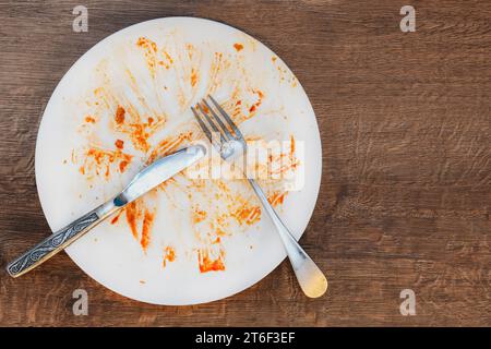 piatto sporco dopo aver mangiato. forcella e coltello su una piastra. Piatto sporco dopo aver mangiato. Fine del pasto. Buon appetito, cibo delizioso e concetto di piatto. vista dall'alto Foto Stock