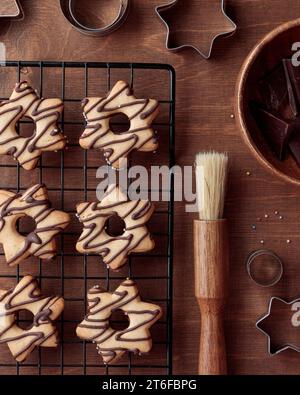 Biscotti fatti in casa a forma di stella appena sfornati con cioccolato sulla griglia sul tavolo di legno Foto Stock