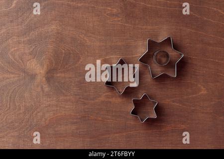 Tre taglierine a forma di stella sullo sfondo di legno marrone scuro, banner orizzontale, vista dall'alto Foto Stock