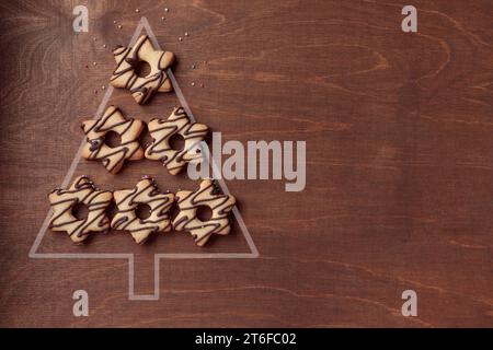 Forma dell'albero di Natale a base di biscotti al pan di zenzero a forma di stella con cioccolato, striscione su fondo di legno marrone Foto Stock