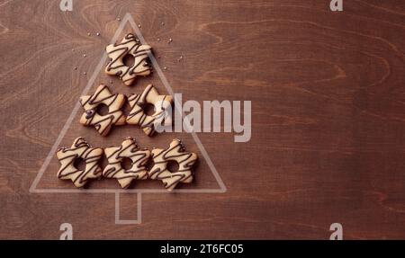 Forma dell'albero di Natale fatta di biscotti a forma di stella con cioccolato, striscione su sfondo marrone di legno con spazio per le copie Foto Stock