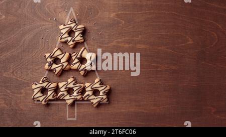 Forma dell'albero di Natale fatta di biscotti a forma di stella con cioccolato, striscione su sfondo marrone di legno con spazio per le copie Foto Stock