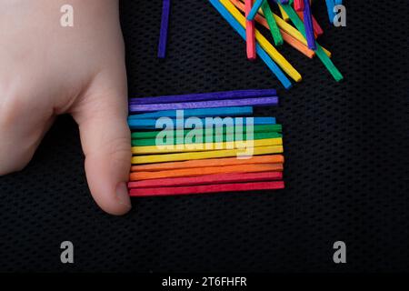 Bambino che gioca con bastoni di legno colorati per la creatività su sfondo bianco Foto Stock