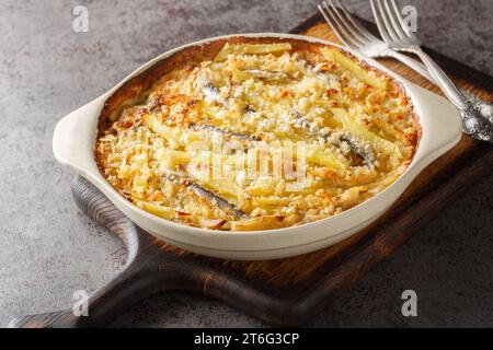 La tentazione di Jansson fatta in casa è fatta con patate, cipolla e spratti primo piano sulla piastra da forno sul tavolo. Orizzontale Foto Stock