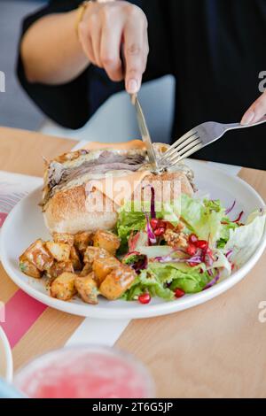 Persona che ha un panino aperto di roast beef con verdure a lato. Foto Stock