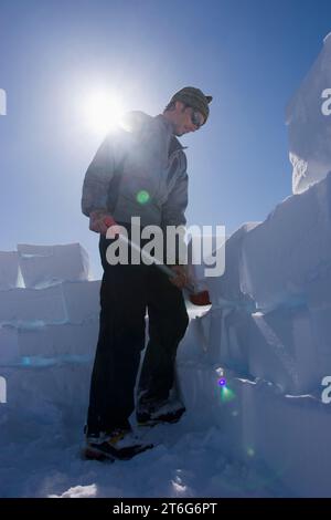 Studente di geologia glaciale PhD costruisce un muro di blocchi di neve intorno alla sua tenda del campo base, Brady Glacier, Glacier Bay National Park, al Foto Stock