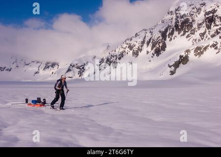 Glacier geologia dottorando sci attraverso il ghiacciaio di Brady, tirando una slitta di apparecchiature geofisiche. Foto Stock