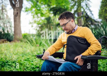 Una persona con disabilità con documenti nel parco Foto Stock