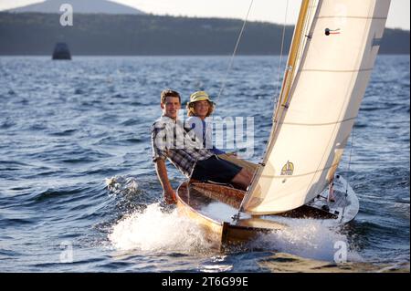 Due ragazzi adolescenti salpano su un classico gommone in legno, in un brillante pomeriggio estivo. Foto Stock