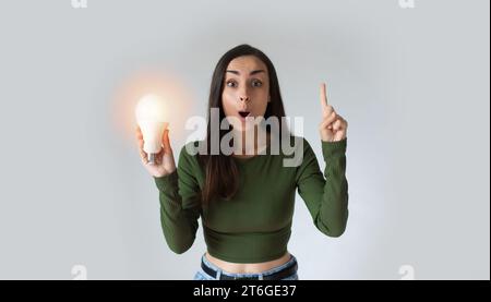 Ragazza con una lampadina a LED. Utilizzo di lampadine economiche ed ecologiche. Lampada a risparmio energetico per le mani delle donne nel settore creativo Foto Stock