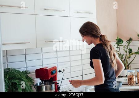 Donna casalinga che cucina il cibo in cucina Foto Stock