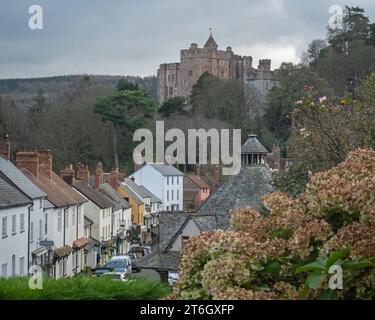 Ammira High Street a Dunster, Somerset, Inghilterra, Regno Unito, mostrando alcuni dei vecchi edifici con il castello di Dunster e le colline di Exmoor in lontananza Foto Stock