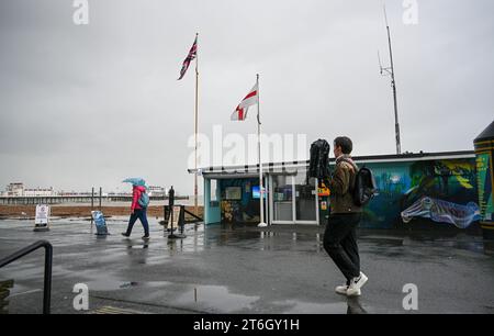 Worthing Regno Unito 10 novembre 2023 - Walkers sul lungomare di Worthing sotto il vento e la pioggia mentre il maltempo è previsto per il Regno Unito : Credit Simon Dack / Alamy Live News Foto Stock