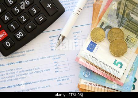 Primo piano sulla compilazione del modulo fiscale francese con calcolatrice, penna e banconote in euro. Periodo e scadenza di pagamento delle imposte Foto Stock