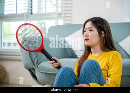Pavimento asiatico femminile con dispositivo di scambio di zanzare o racchetta di rete elettrica Foto Stock