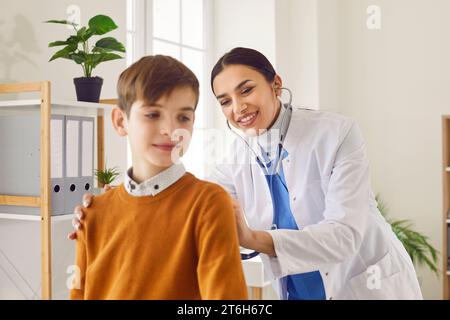 La pediatra donna felice e sorridente usa uno stetoscopio per esaminare un bambino Foto Stock