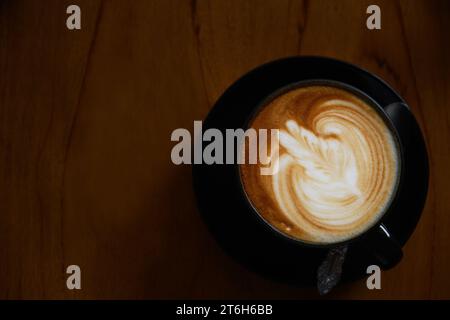 Vista dall'alto della tazza di caffè con la splendida latte art su sfondo in legno, concetto di caffè Foto Stock