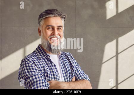 Ritratto di un uomo maturo barbuto sorridente e sorridente in camicia casual con braccia incrociate Foto Stock