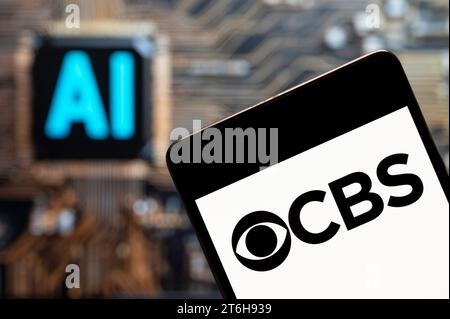 In questa immagine fotografica, il logo CBS della rete televisiva e radiofonica in lingua inglese americana è visualizzato su uno smartphone con un chip di intelligenza artificiale (ai) e un simbolo sullo sfondo. Foto Stock