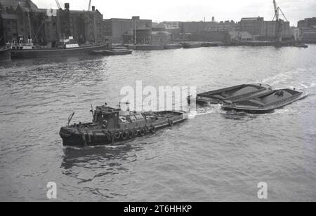 Anni '1950, storico, un rimorchiatore a vapore, iniziali B & D sul lato, tirando due chiatte caricate con merci, materie prime, sul fiume Avon ai moli di Bristol, Inghilterra, Regno Unito. Foto Stock