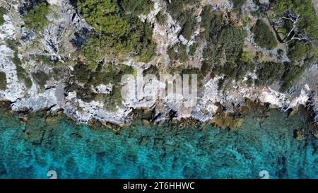 Vista aerea di uno splendido paesaggio oceanico caratterizzato da vivaci acque blu circondate da lussureggianti alberi verdi e grandi massi grigi Foto Stock