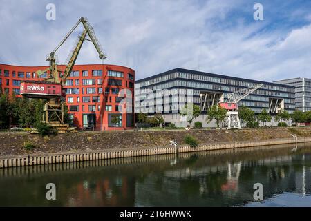 Duisburg, regione della Ruhr, Renania settentrionale-Vestfalia, Germania - porto interno di Duisburg con l'edificio a forma d'onda dell'archivio statale della Renania settentrionale-Vestfalia e vecchie gru portuali. Sul lato destro degli edifici moderni per uffici. Foto Stock