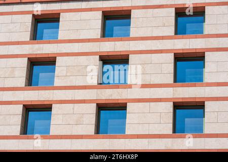 Telai in vetro blu. Ripetizione e trama. Facciata in stile architettonico beige di colore rosso. Giornata di sole. Foto Stock