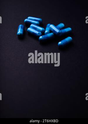 Capsule di aminoacidi su sfondo di carta scura. Messa a fuoco morbida. Primo piano. Copia spazio. Foto Stock