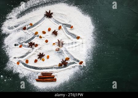 Albero di Natale con stella di anice, sultani o uvetta gialla e corteccia di cannella su sfondo verde. Vista da tavolo Foto Stock