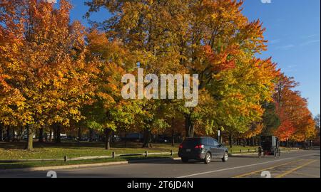 Un'auto segue dietro un buggy Amish passando davanti al villaggio commons a Burton, Ohio. Foto Stock