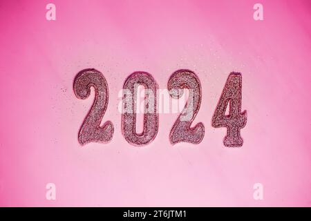 Capodanno 2024. Numeri del prossimo anno su sfondo rosa. Il colore alla moda dell'anno uscente nello stile di una bambola alla moda Foto Stock