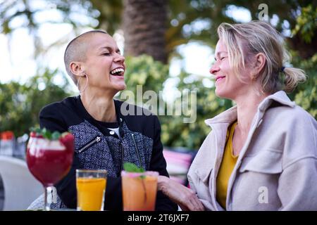 Sorelle caucasiche mature e allegri che si incontrano sedute sulla terrazza del ristorante sorridendo sorridenti sorridenti Foto Stock
