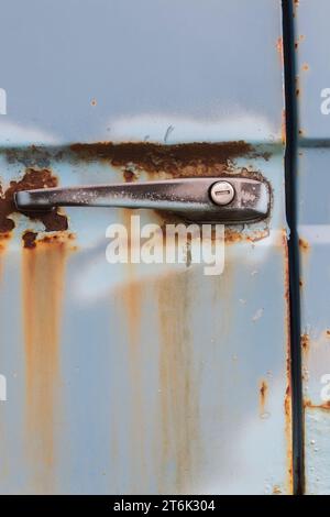 Macchie di ruggine e maniglia con foro sulla porta del vecchio carrello blu. Foto Stock