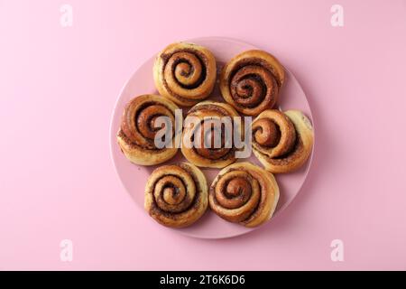 Molti gustosi dolci alla cannella, sfondo rosa, vista dall'alto Foto Stock