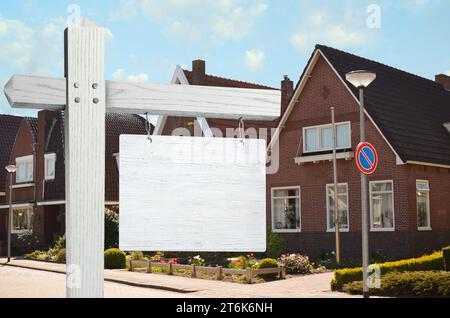 Cartello di legno bianco vuoto vicino a una bella casa all'aperto Foto Stock