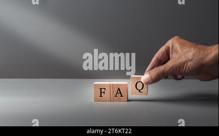 Domande frequenti sulle pose delle mani, domande frequenti, domande frequenti sul testo, scritte su cubi di legno su sfondo blu grigio, concetto di servizio clienti o assistenza. Foto Stock