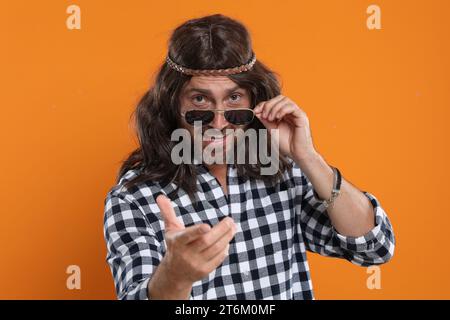 Uomo hippie con occhiali da sole su sfondo arancione Foto Stock