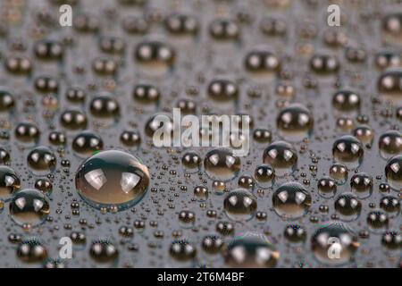 gocce d'acqua sulla superficie dello schermo del cellulare, primo piano con messa a fuoco selettiva e sfocatura Foto Stock