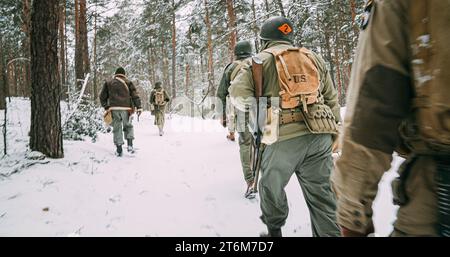 Soldato di fanteria americano, è difficile attraversare Forest Road nel freddo inverno. Squadra militare USA Marching by Country Road. Soldati dell'esercito degli Stati Uniti d'America del mondo Foto Stock